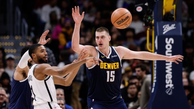 Brooklyn Nets forward Mikal Bridges (1) passes the ball under pressure from Denver Nuggets center Nikola Jokic (15)